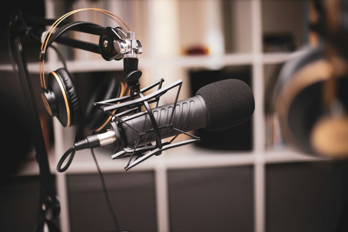 A studio microphone and headphones on a shelf